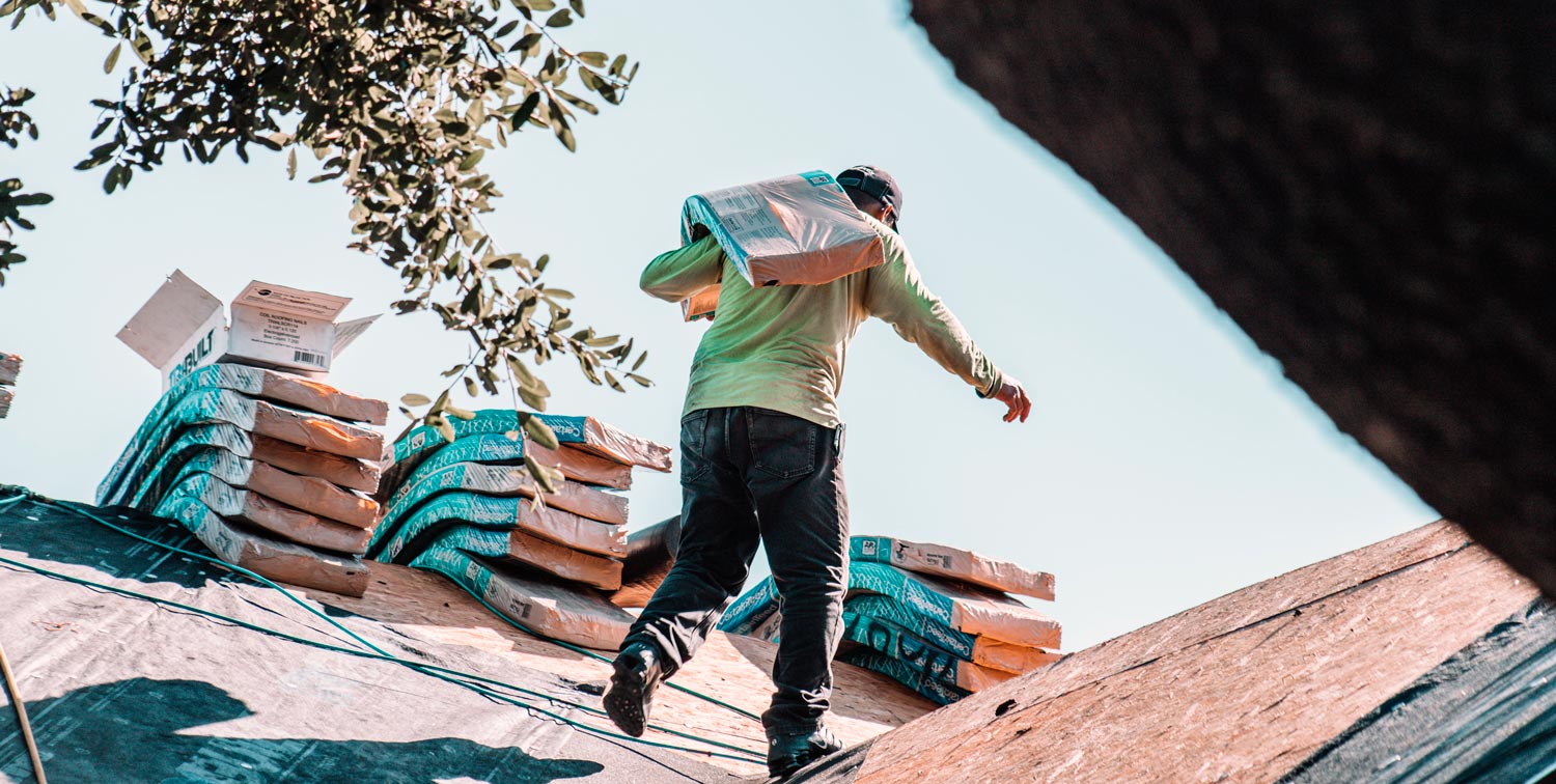 A man carrying roofing materials for roof work